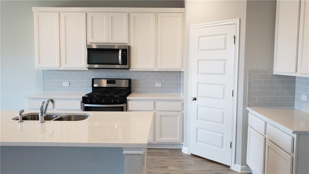 1508 Whippletree Trail Georgetown, TX 78626 - Photo 10 of 30 a kitchen with white cabinets and black appliances