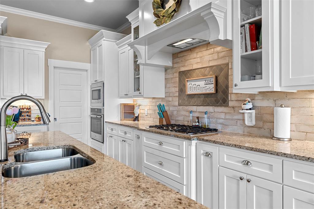 23 Independence Trail Waco, TX 76708 - Photo 10 of 35 Gourmet kitchen featuring a dual-basin stainless steel sink, granite countertops, white cabinetry, a natural brick backsplash, and built-in stainless steel appliances