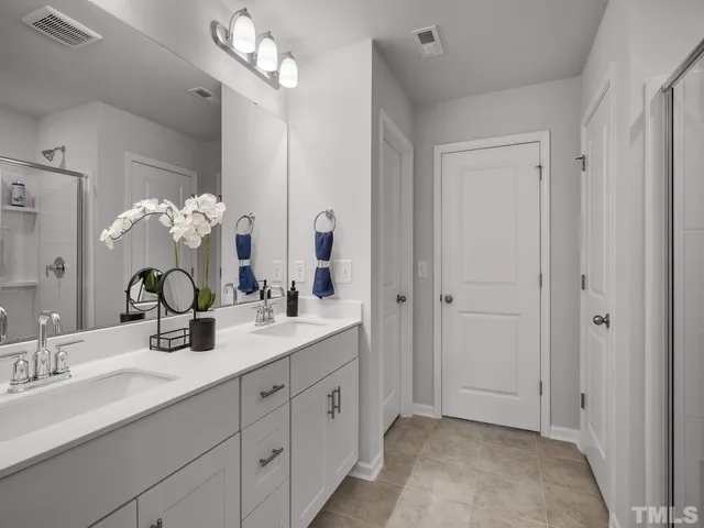 a bathroom with a double vanity sink mirror and chandelier