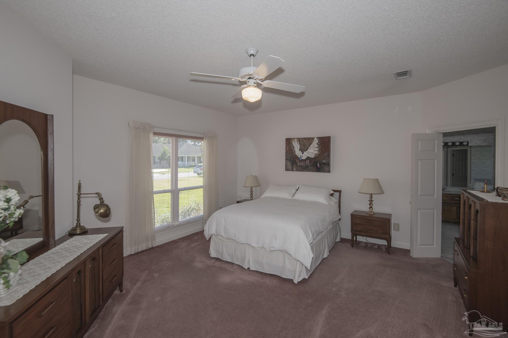 1505 Kings Road Cantonment, FL 32533 - Photo 25 of 57 a spacious bedroom with a bed and a chandelier