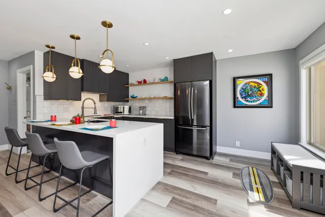 a kitchen with stainless steel appliances granite countertop a refrigerator a sink dishwasher a dining table and chairs with wooden floor