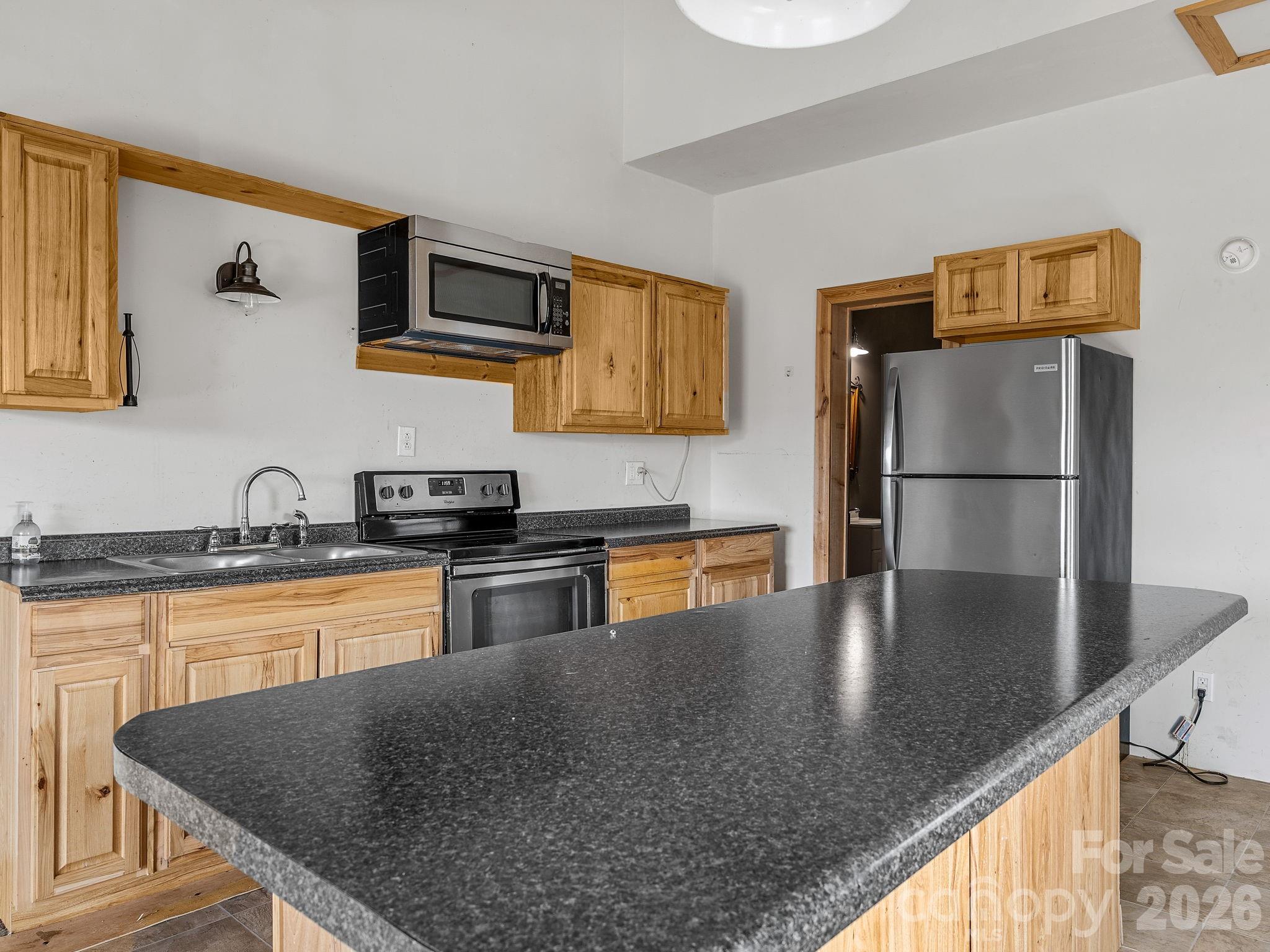 1487 Hayes Road Columbus, NC 28722 - Photo 6 of 48 a kitchen with stainless steel appliances granite countertop a refrigerator a stove and a sink with wooden floor