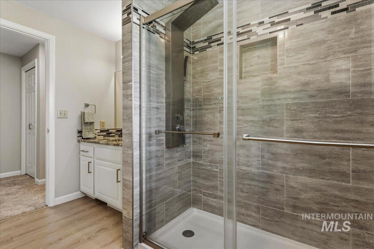 599 Pebble Beach Way Eagle, ID 83616 - Photo 29 of 44 Glass-enclosed shower with gray stone-look wall tiling and a tiled accent stripe