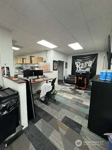a living room with stainless steel appliances furniture a rug kitchen view and a fireplace