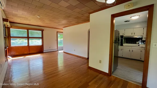 a view of a hallway with wooden floor and a kitchen