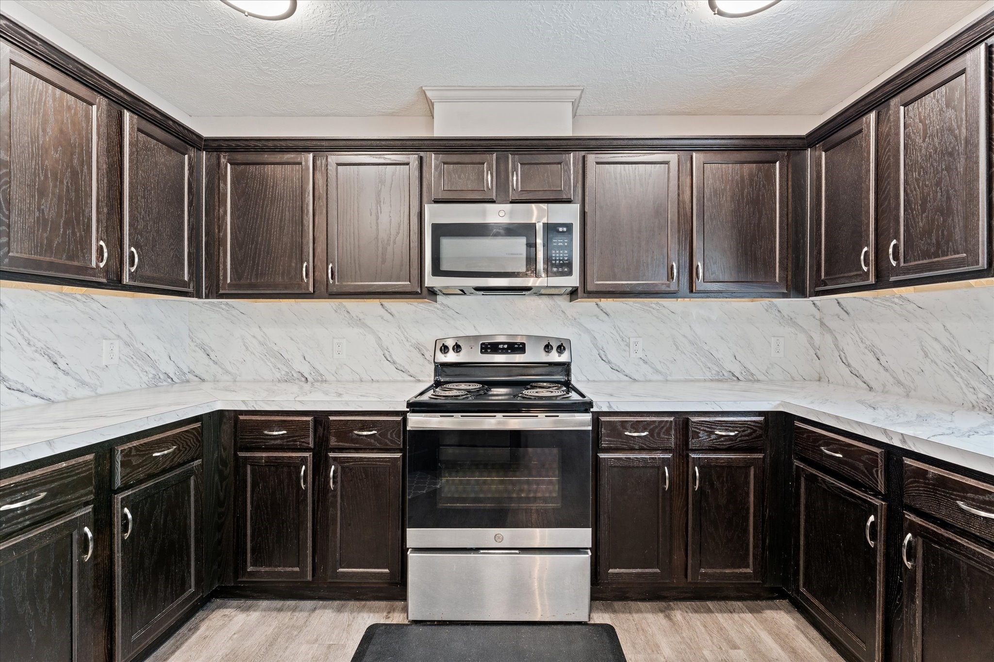 3998 Frontier Road Willis, TX 77378 - Photo 22 of 33 a kitchen with granite countertop a stove top oven microwave and cabinets