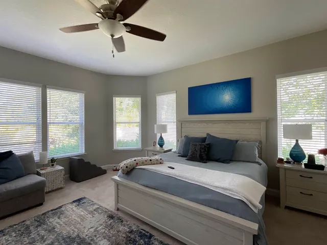 a living room with lots of furniture kitchen view and a large window