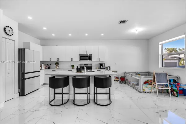 a kitchen with kitchen island a stove a refrigerator and a dining table with wooden floor