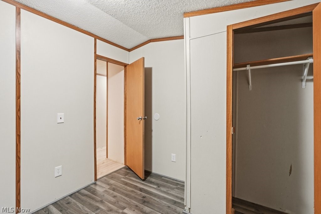 6507 Robby Lane Ravenna, OH 44266 - Photo 22 of 25 Unfurnished bedroom featuring a textured ceiling, wood finished floors, a closet, and ornamental molding