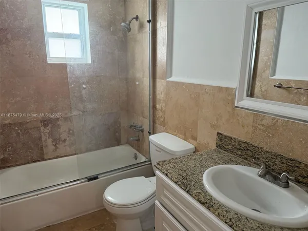 a bathroom with a granite countertop toilet sink and mirror