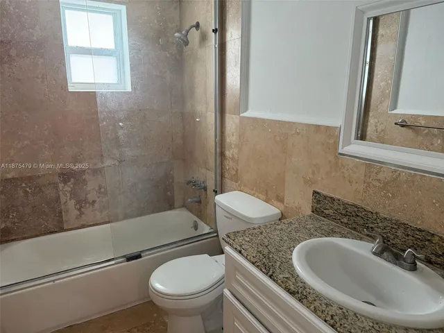 a bathroom with a granite countertop toilet sink and mirror