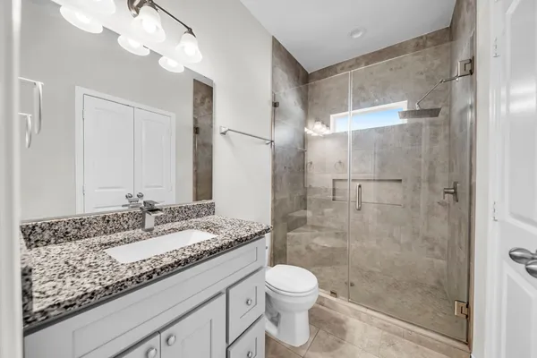 a bathroom with a granite countertop sink a toilet and shower