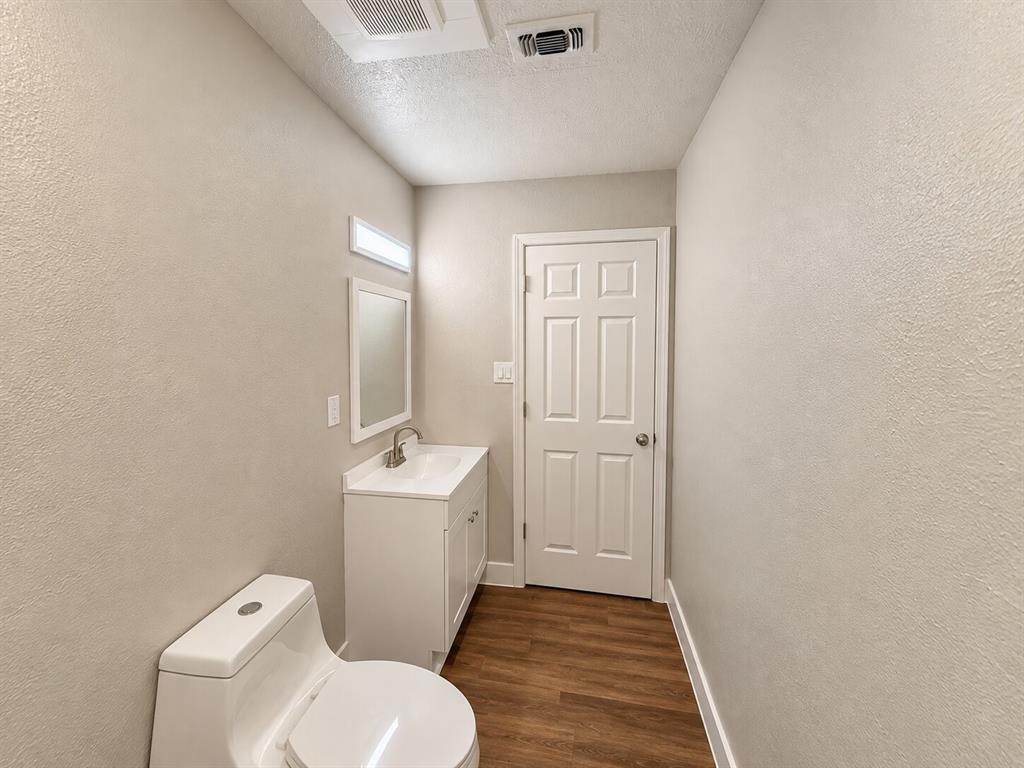 2002 Washington Street, Unit 3 Commerce, TX 75428 - Photo 7 of 8 White vanity with an integrated sink, framed mirror, and wood-finish flooring
