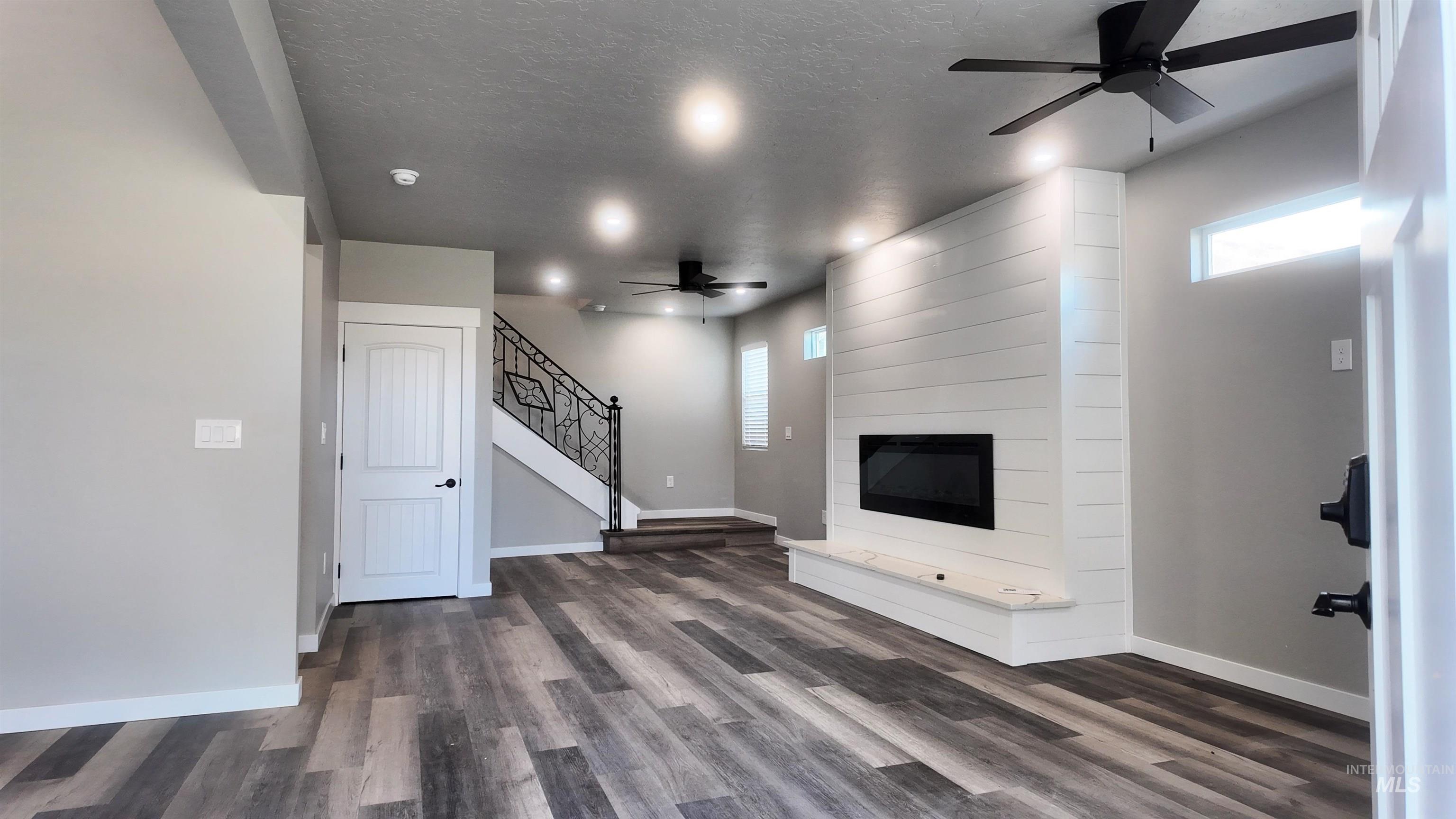 5850 Lockett Road Huntington, OR 97907 - Photo 17 of 49 Unfurnished living room featuring a ceiling fan, plenty of natural light, a fireplace, dark wood finished floors, and a textured ceiling