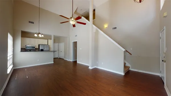 a view of an empty room with wooden floor and a ceiling fan