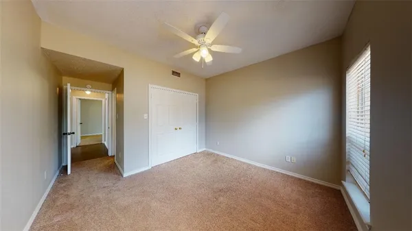an empty room with closet and a chandelier fan
