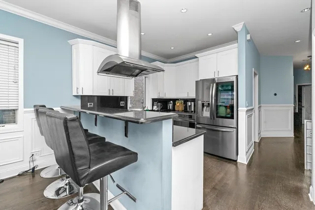 a kitchen with stainless steel appliances kitchen island granite countertop a table chairs microwave and sink