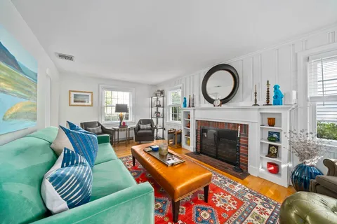 a living room with furniture a fireplace a large window and a flat screen tv