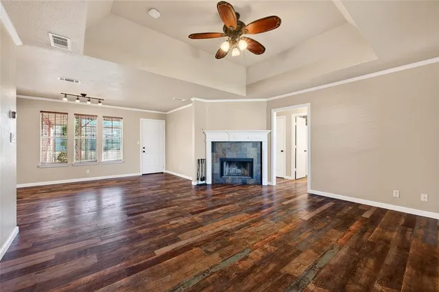 a view of an empty room with wooden floor fireplace and a window