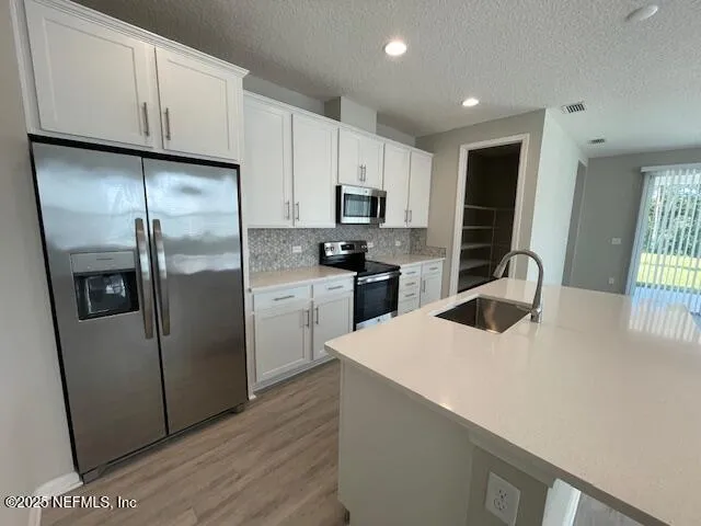 a kitchen with stainless steel appliances a refrigerator sink and microwave