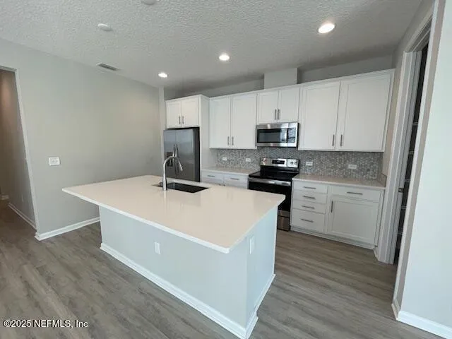 a kitchen that has a lot of cabinets and wooden floor