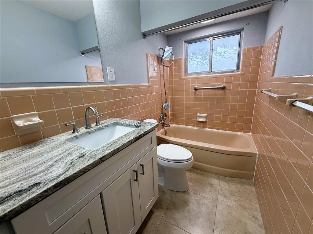 500 140th Avenue East Madeira Beach, FL 33708 - Photo 22 of 30 a bathroom with a granite countertop sink a toilet and bathtub