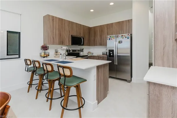 a kitchen with stainless steel appliances a table chairs refrigerator and microwave