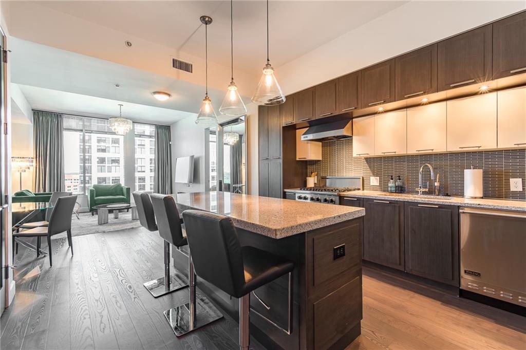 1820 Peachtree Road Northwest, Unit 1111 Atlanta, GA 30309 - Photo 1 of 41 a kitchen with a stove a sink dishwasher a dining table and chairs with wooden floor