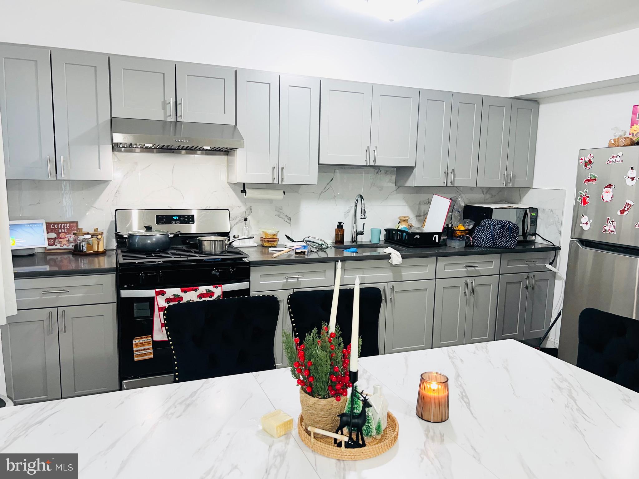 3019 St Vincent Street Philadelphia, PA 19149 - Photo 10 of 33 a kitchen with stainless steel appliances kitchen island granite countertop a sink dishwasher and cabinets with wooden floor