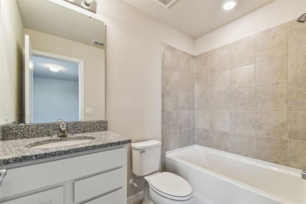 6885 Southwest 90th Place Ocala, FL 34476 - Photo 16 of 23 a bathroom with a granite countertop sink a toilet and bathtub