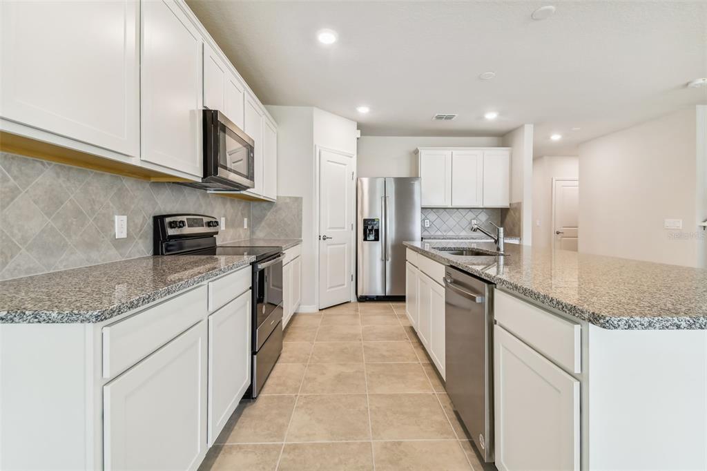6885 Southwest 90th Place Ocala, FL 34476 - Photo 5 of 23 a large kitchen with stainless steel appliances granite countertop a stove a sink and a microwave