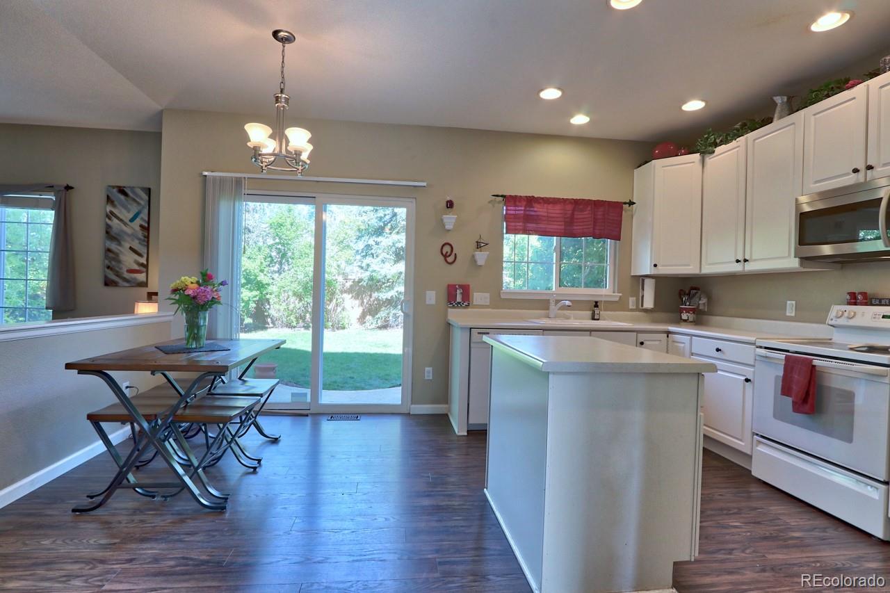 9818 Mulberry Way Highlands Ranch, CO 80129 - Photo 12 of 34 a open kitchen with stainless steel appliances granite countertop a stove top oven a sink dishwasher a dining table and chairs with wooden floor