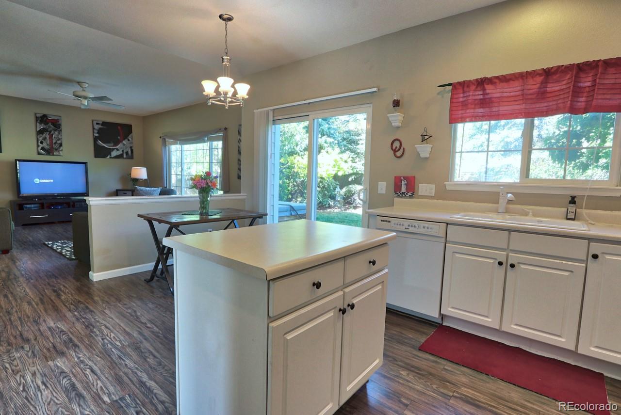 9818 Mulberry Way Highlands Ranch, CO 80129 - Photo 14 of 34 a kitchen with a sink dishwasher a dining table and chairs with wooden floor