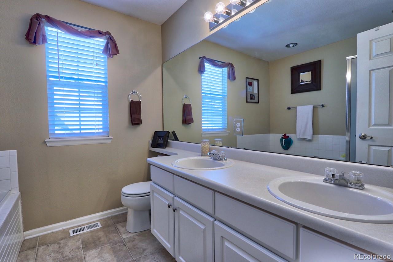 9818 Mulberry Way Highlands Ranch, CO 80129 - Photo 21 of 34 a bathroom with a double vanity sink toilet and mirror