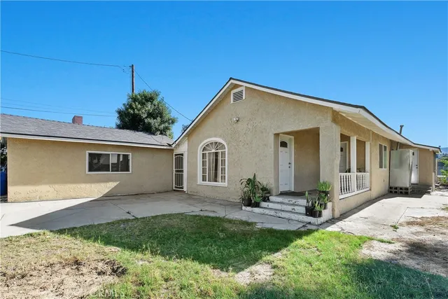 a front view of a house with a yard and potted plants