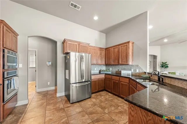 a kitchen with stainless steel appliances granite countertop a sink refrigerator and cabinets