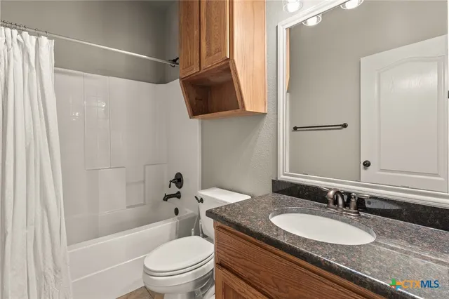 a bathroom with a granite countertop sink toilet a mirror and shower