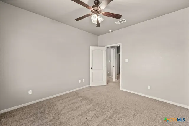 a view of an empty room and chandelier fan