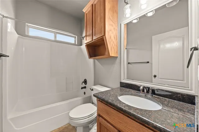 a bathroom with a granite countertop sink a toilet a mirror and shower