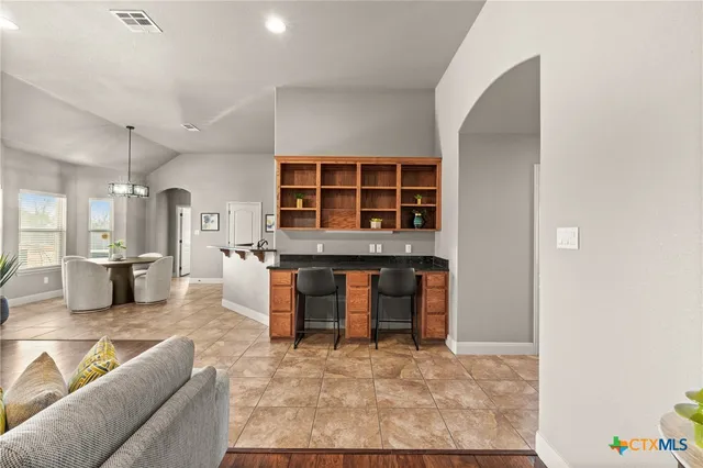 a living room with furniture a flat screen tv and kitchen view