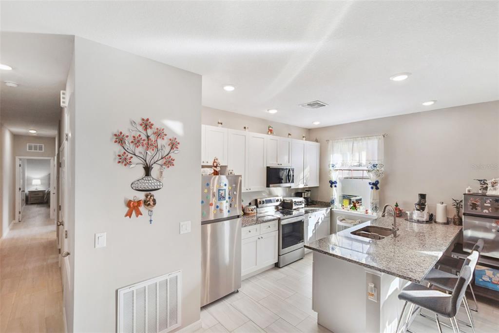 1021 Titcomb Street Eustis, FL 32726 - Photo 18 of 40 a kitchen with stainless steel appliances kitchen island granite countertop a refrigerator a sink a stove and white cabinets with wooden floor