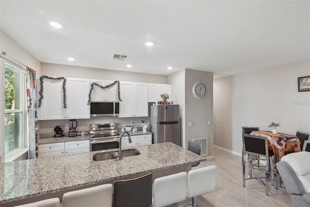 1021 Titcomb Street Eustis, FL 32726 - Photo 25 of 40 a kitchen with stainless steel appliances granite countertop a sink refrigerator and cabinets