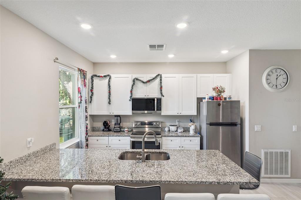 1021 Titcomb Street Eustis, FL 32726 - Photo 26 of 40 a kitchen with granite countertop a refrigerator and a stove top oven