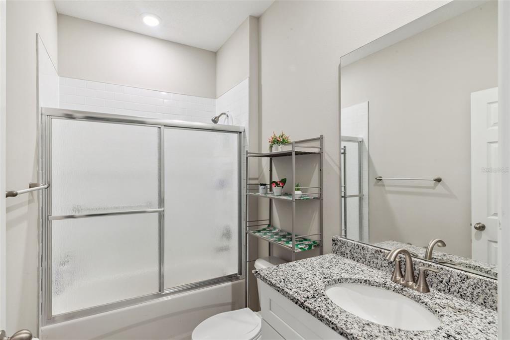 1021 Titcomb Street Eustis, FL 32726 - Photo 29 of 40 a bathroom with a granite countertop sink mirror shower and toilet