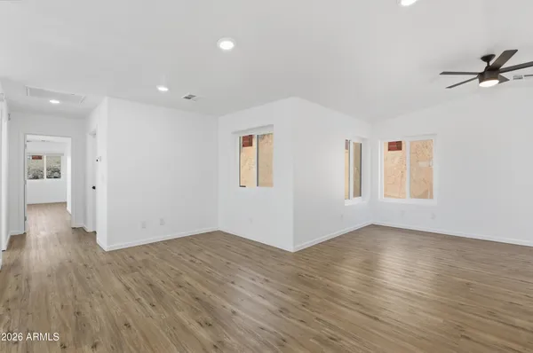 a view of an empty room with wooden floor and a window