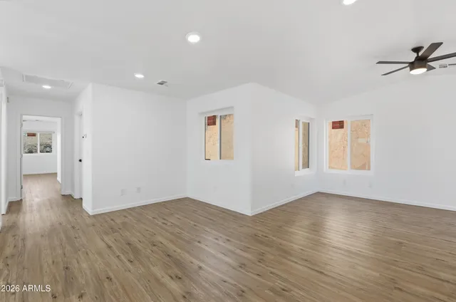 a view of an empty room with wooden floor and a window