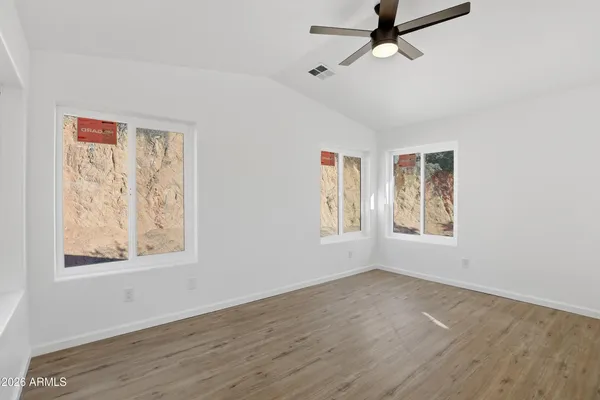 a view of an empty room with a window and wooden floor