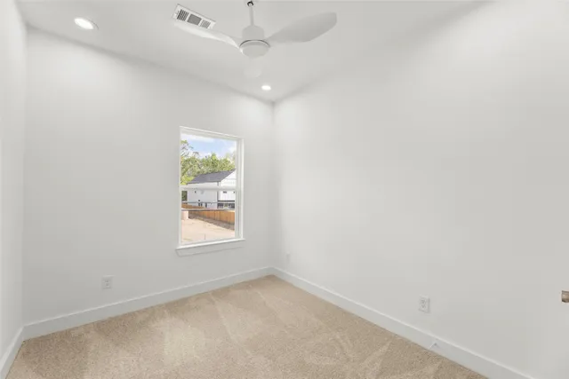 an empty room with window and ceiling fan