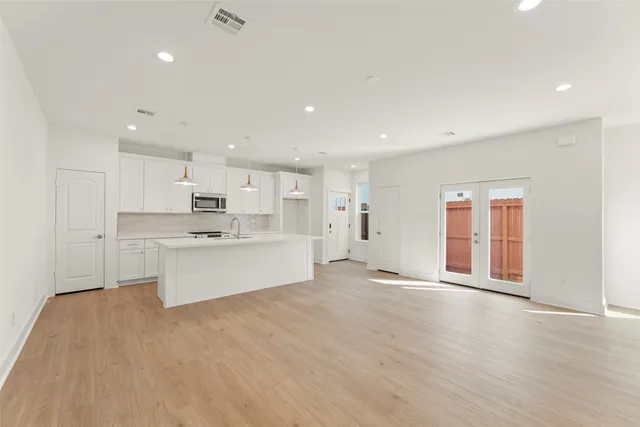 a view of large kitchen with wooden floor and stainless steel appliances