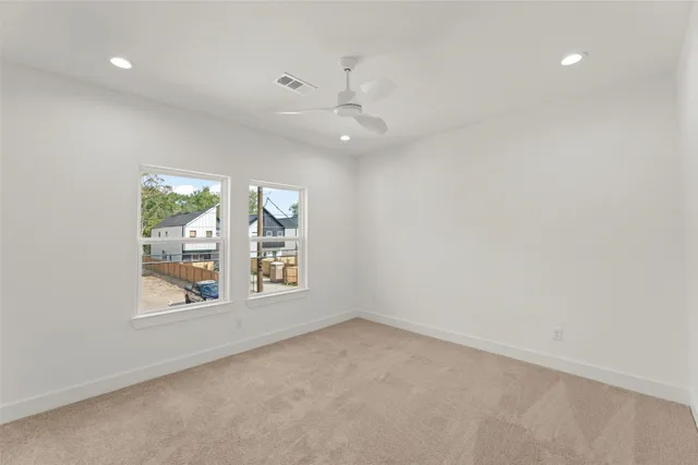 an empty room with windows and ceiling fan